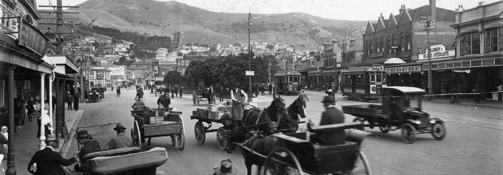 A black and white photo of Courtenay Place in 1910 with horse and carts riding beside early motorcars.