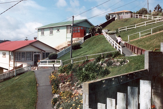 A woman walks up a steep zig zag path on the side of a hill in Rongotai.