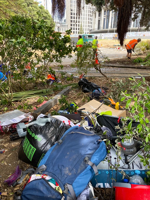 A large pile of rubbish left over from the protest sits in a bush.