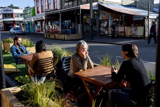 Two parklets on upper Cuba Street with tables and chairs and customers.