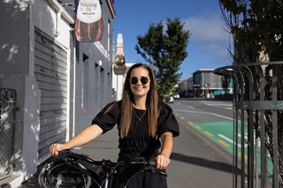 Woman with sunglasses on holding onto her bike.