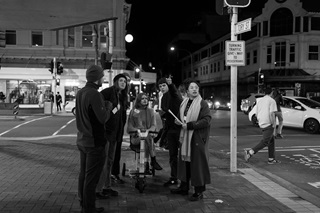 Group of six people standing on a street corner.