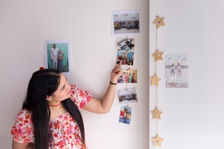 A woman pointing at photos hanging down the wall.