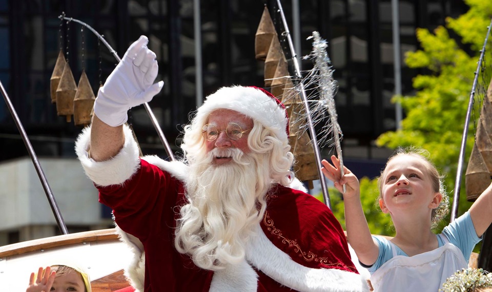 Santa waves to the crowds at A Very Welly Christmas event with young girl beside him