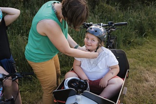 Woman putting a helmet on a child.