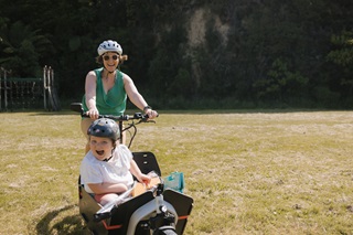 Woman cycling with her child in a cargo bike.