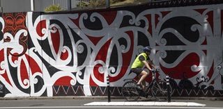 Cyclist passing by the Ariki Brightwell mural.