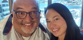 A close-faced selfie of Leo Koziol smiling with a shaved head and black-rimmed reading glasses next to a smiling Wellington Mayor, Tory Whanau, with long black hair and shiny lips.
