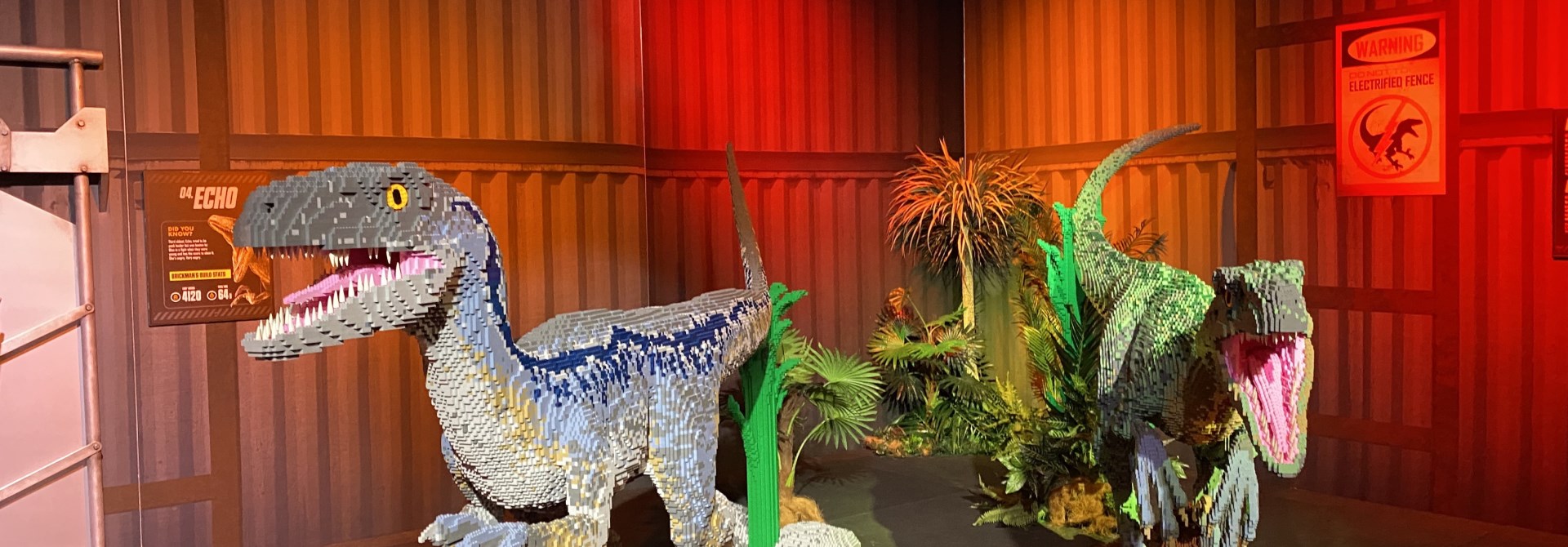 Lego exhibition with two dinosaurs made up of lego infront of a red curtain.