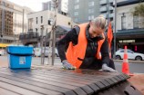 Person scrubbing down seats on Courtenay Place.