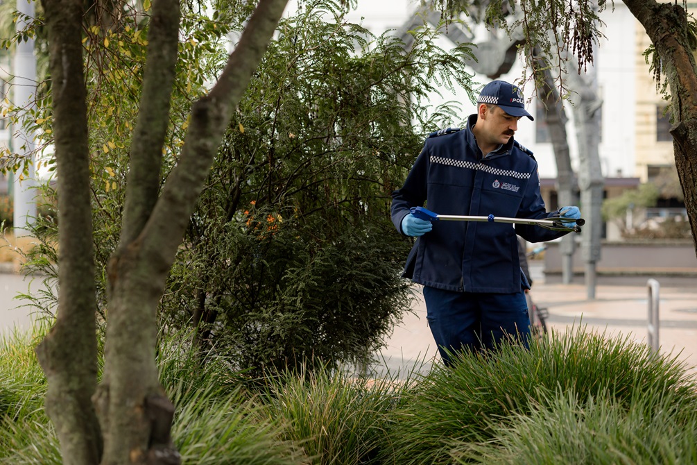Police picking up rubbish in a bush.