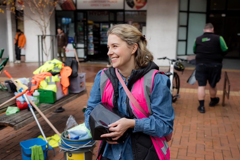 Woman wearing a high vis pink jacket and smiling.
