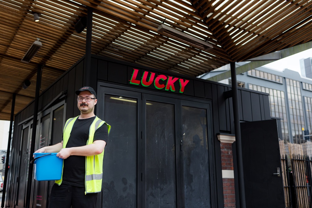 Man wearing a yellow high vis jacket standing outside of Lucky chicken.
