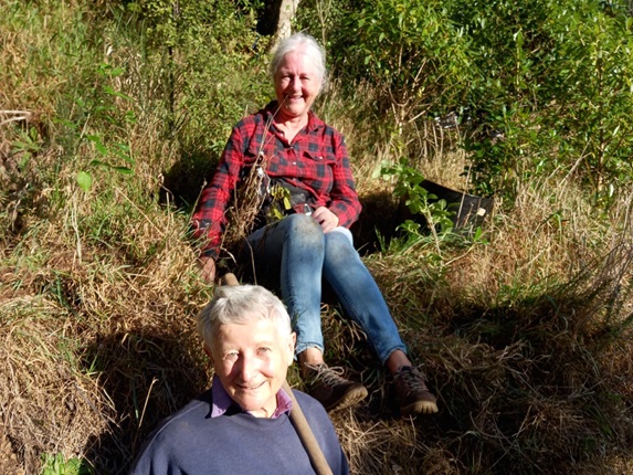 Two women sitting on a bank doing volunteer work.