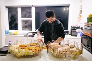 Man cooking in a kitchen with two baskets of food.