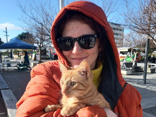Woman wearing an orange hoodie holding up a cat.