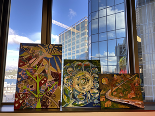 Three canvas artworks sitting on a window sill. 