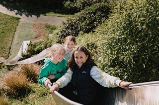 Three young girls sitting on a slide and smiling.
