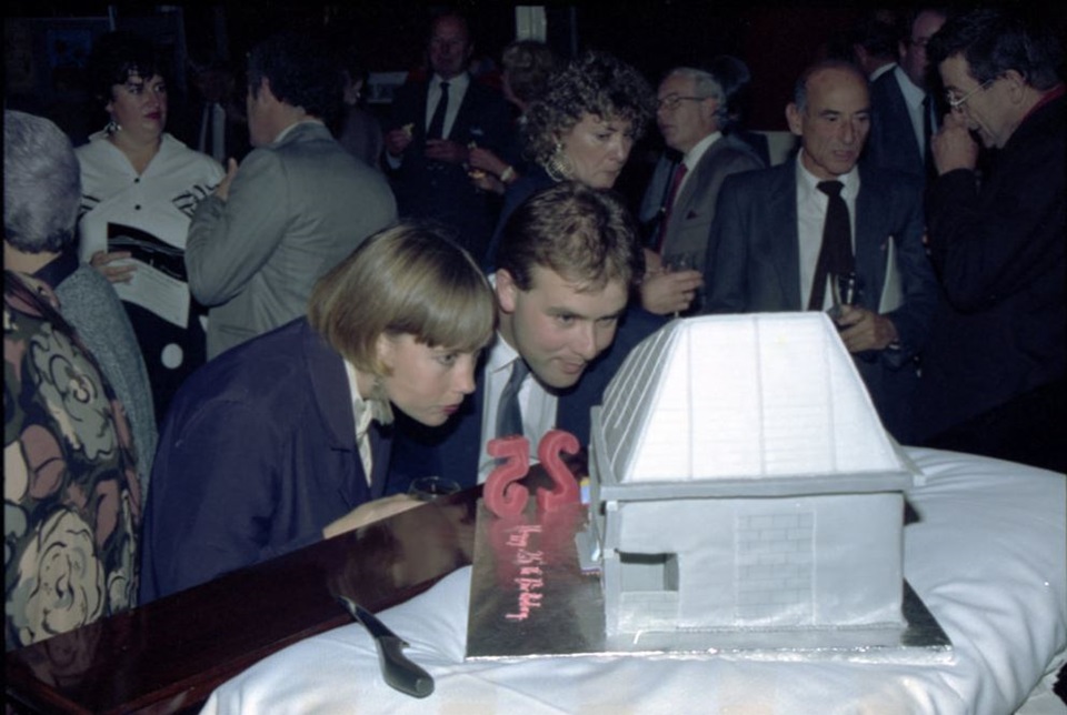 Couple of people look at cake of Hannah Playhouse at 25th anniversary celebrations