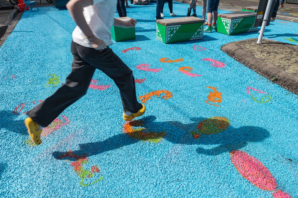 Child walks across blue painted road at launch of Lyall Bay street trial
