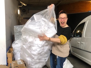 Woman holding up a big bag of foam.