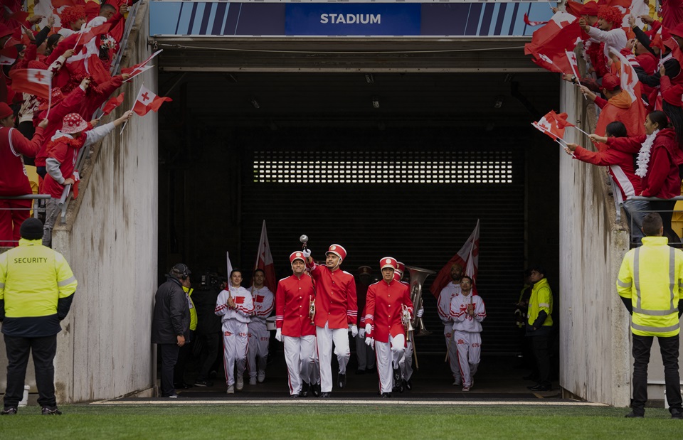 Still from the film Red White and Brass with cast coming out of tunnel at Wellington Stadium