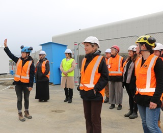 A group of women wearing orange high-vis vests and hard hats on a construction site.