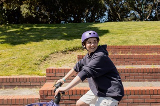 Student smiling on a bike with a purple helmet on.