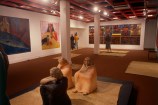 An exhibition at City Gallery Wellington featuring sculptures by Shona Davies of figures sitting on the floor and bright colourful paintings of Māori women by Robyn Kahukiwa.