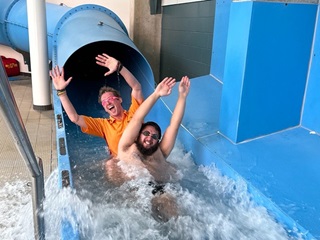 Two lifeguards coming out of a waterslide.