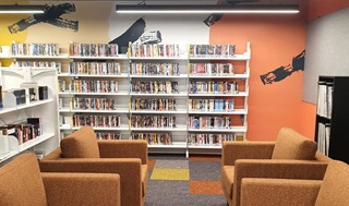 Library book shelves with orange seats infront.