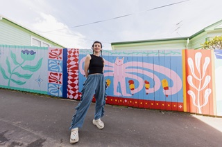 Person standing infront of a mural with colourful images.