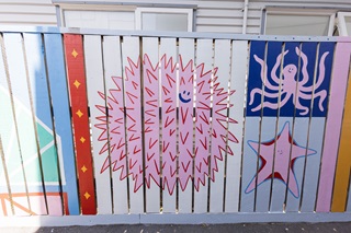 Pink creatures painted on a fence as part of a mural.