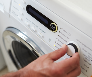 Person turning on a washing machine.