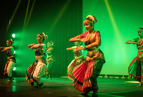 Young people engaging in traditional dance on a stage.