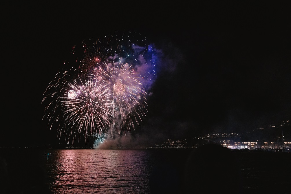 Fireworks exploding over a harbour at night.