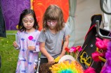 Two children with painted faces search through costume accessories.