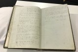 An old book opened up on a table, showing meeting minutes.