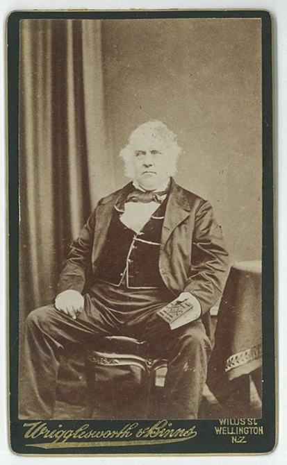 Photographic portrait of a man wearing a suit and waistcoast, posed in a seated position.