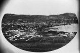 A historical photograph of Wellington harbour, with small settlements around the shoreline.