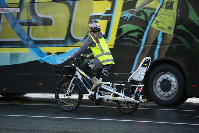 Cyclist on cargo bike riding alongside a bus