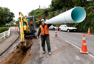 Man carrying pipe on roadside.