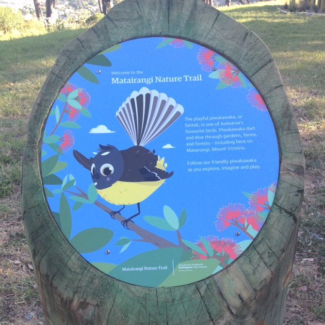 A signpost describing the pīwakawaka at the entrance to the matairangi nature trail.