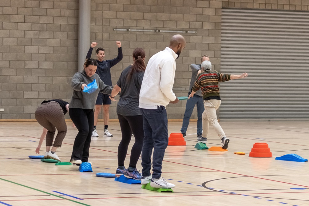 A group of adults stepping on brightly coloured stepping stones as part of a team building exercise.