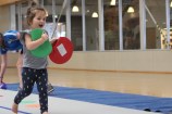 Toddler running in a gym holding a green and a red circle.