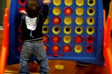 Child playing with a giant Connect Four game at a birthday party.