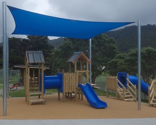 Nairnville park, with teo blue slides, a tunnel, shade sail and inground trampoline.