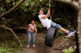 Two children playing on a tyre swing.