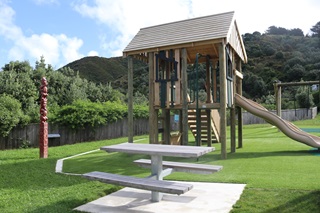 The slide, swings and picnic table at Owhiro Bay play area.
