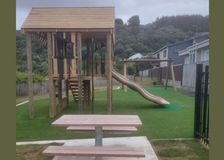 The slide, swings and picnic table at Owhiro Bay play area.